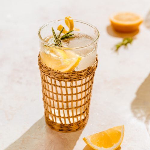 A rattan glass filled with Sparkling Rosemary Ginger Lemonade