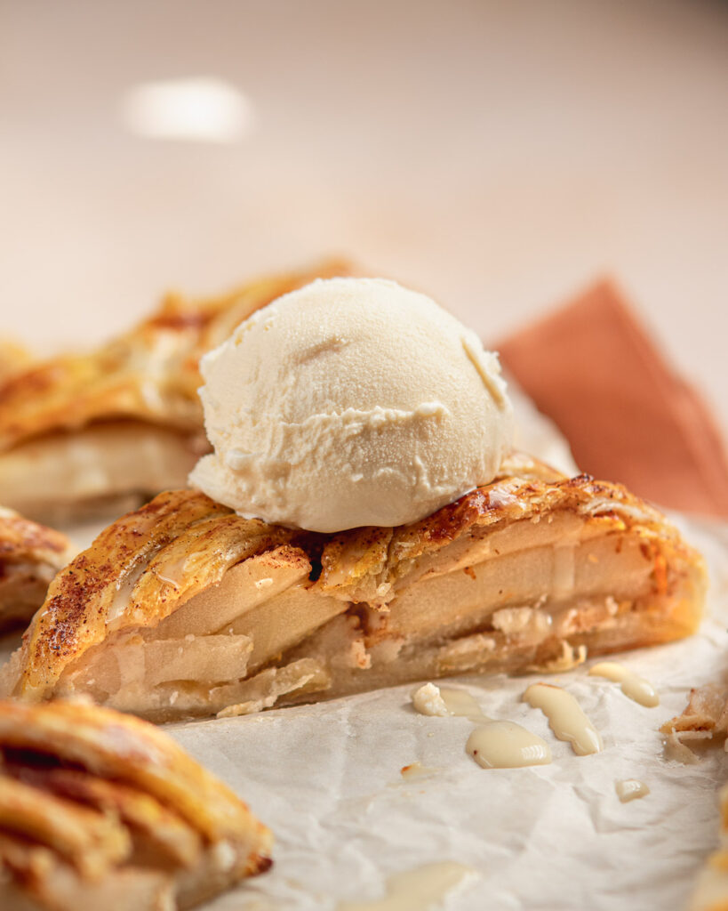 A slice of Apple strudel with vanilla ice cream dripping down on top