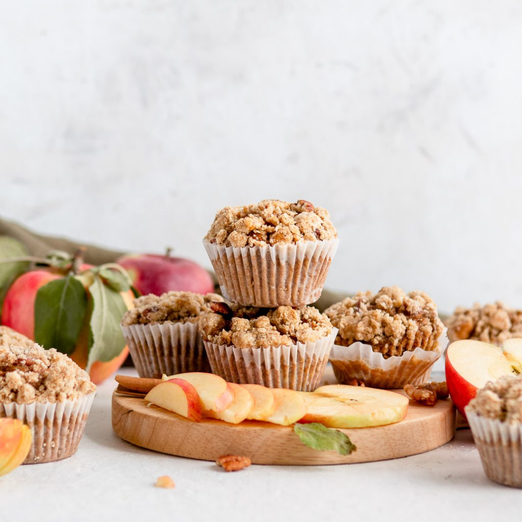 Stacked muffins on a cutting board with sliced apples