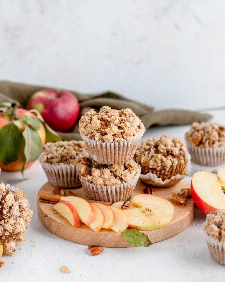 Stacked muffins on a cutting board with sliced apples