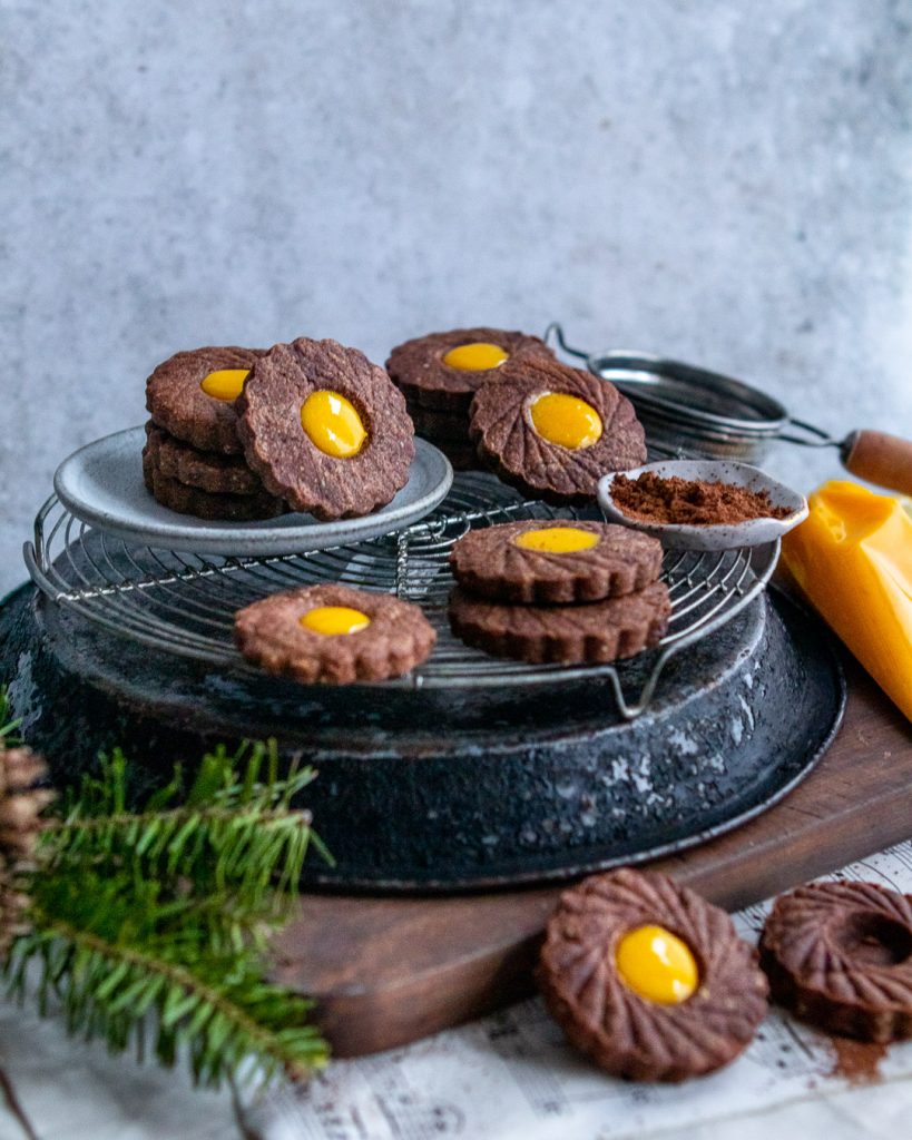 chocolate lemon curd linzer cookies stacked on a cooling rack