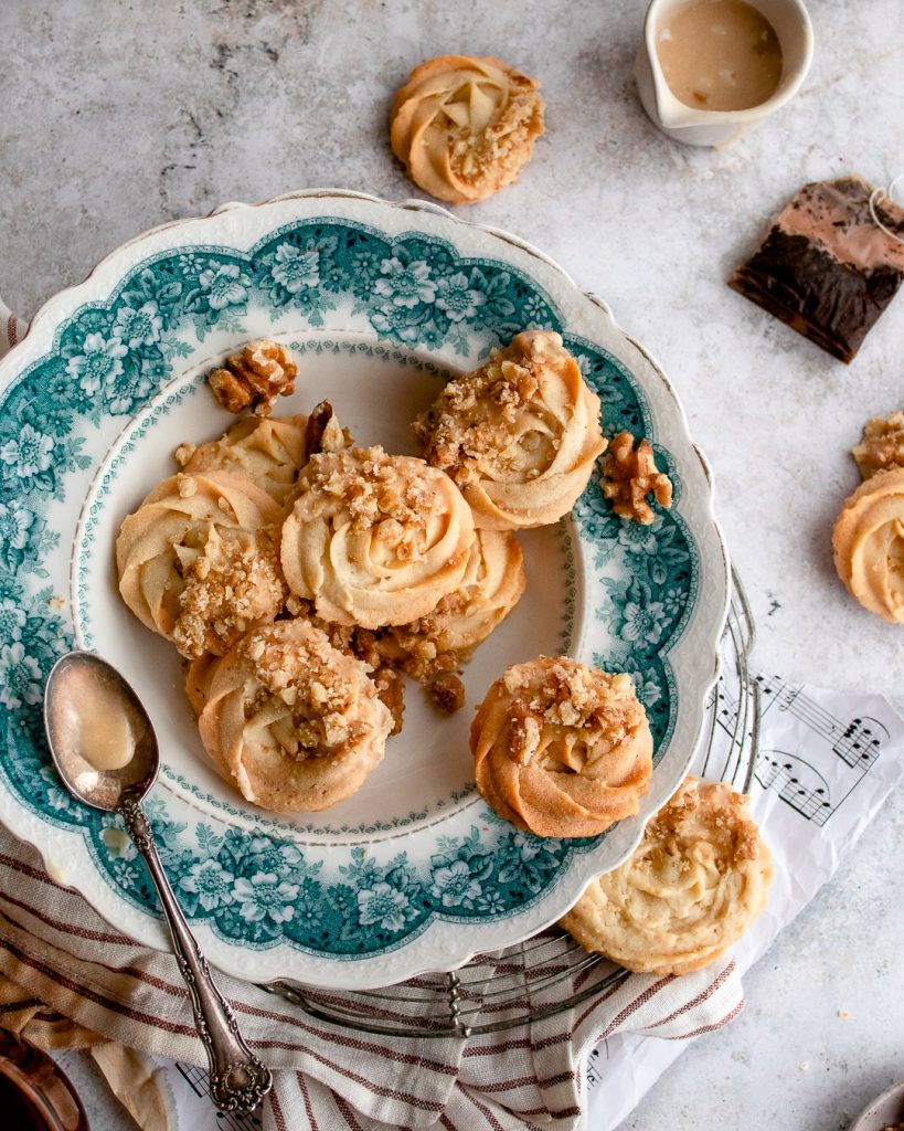 Swirled butter Viennese Whirls topped with a maple glaze and served on a vintage green platter with tea.