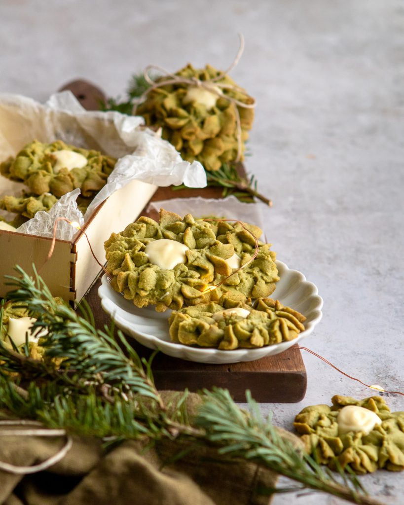 Matcha White chocolate wreath cookies surrounded by fairy lights and on a white scalloped dish
