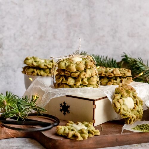 Matcha green tea white chocolatecookies stacked on a cutting board.