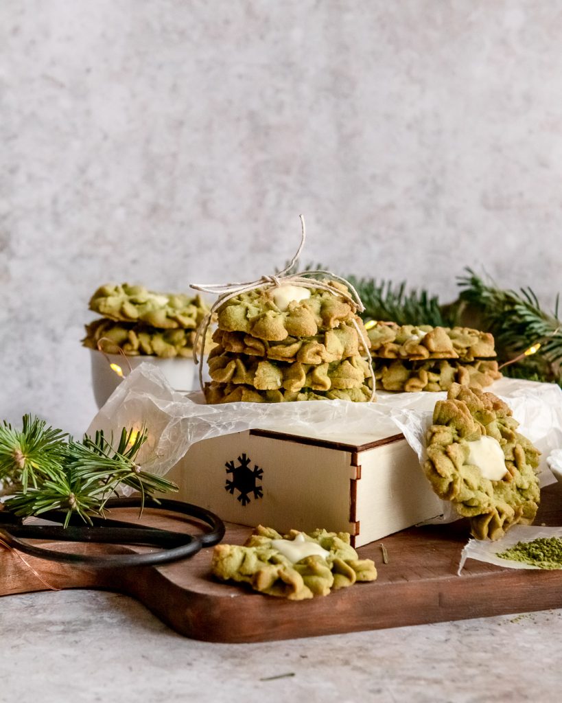 Matcha green tea white chocolatecookies stacked on a cutting board.