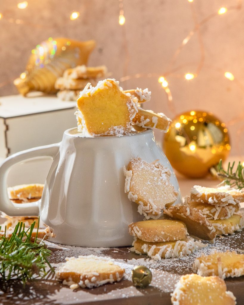 Star butter cookies stacked on a mug with golden christmas decorations