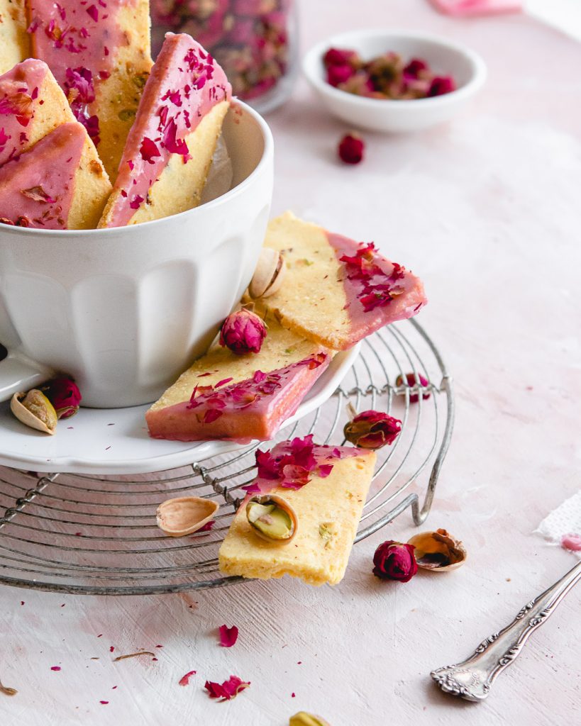 Rose cookies with pink glaze on a wire rack