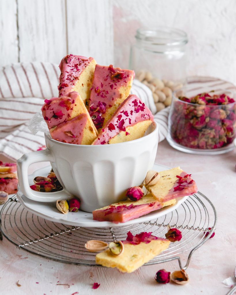 Pistachio rose ice box cookies stacked in a tea cup