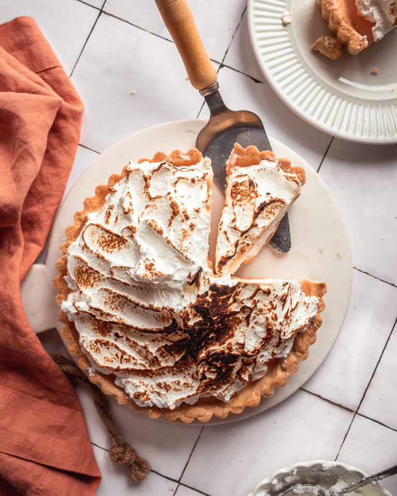 Cutting into a blood orange meringue tart