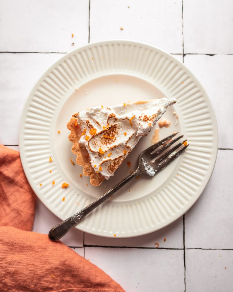 a slice of blood orange meringue tart on a plate