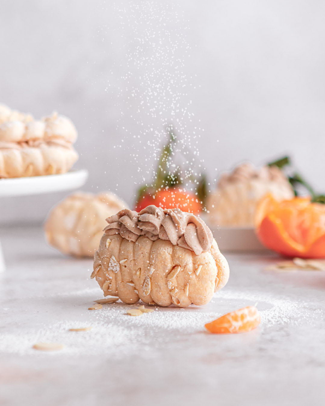 powdered sugar being dusted over a clementine mocha meringue sandwich cookie