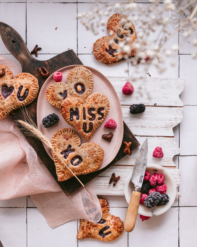 heart hand pies on a pink platter with fresh berries