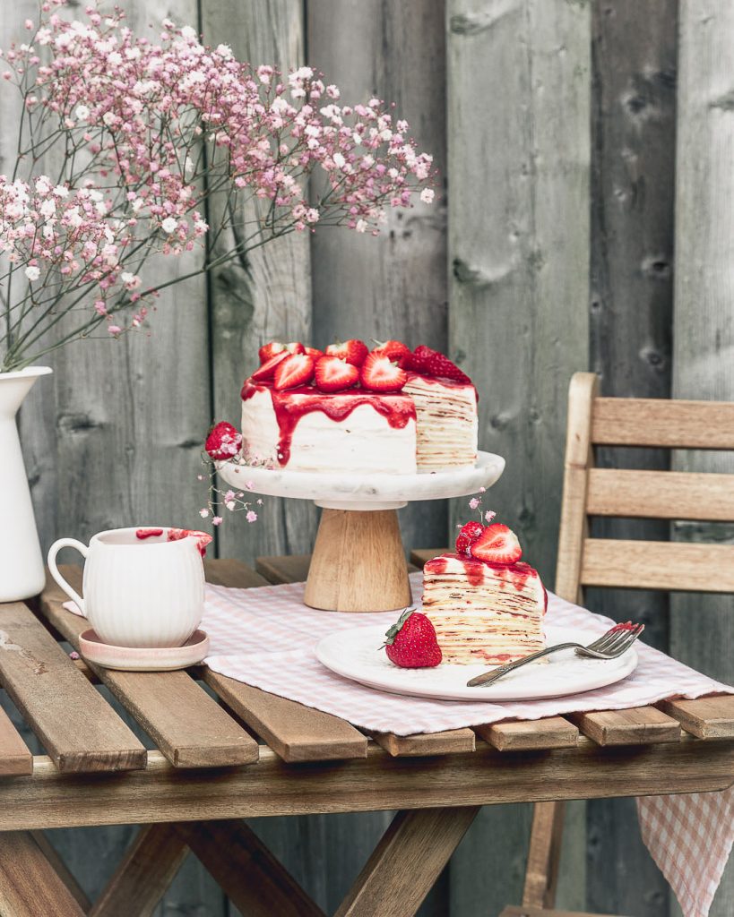 a strawberry vanilla crepe cake with a slice on a plate