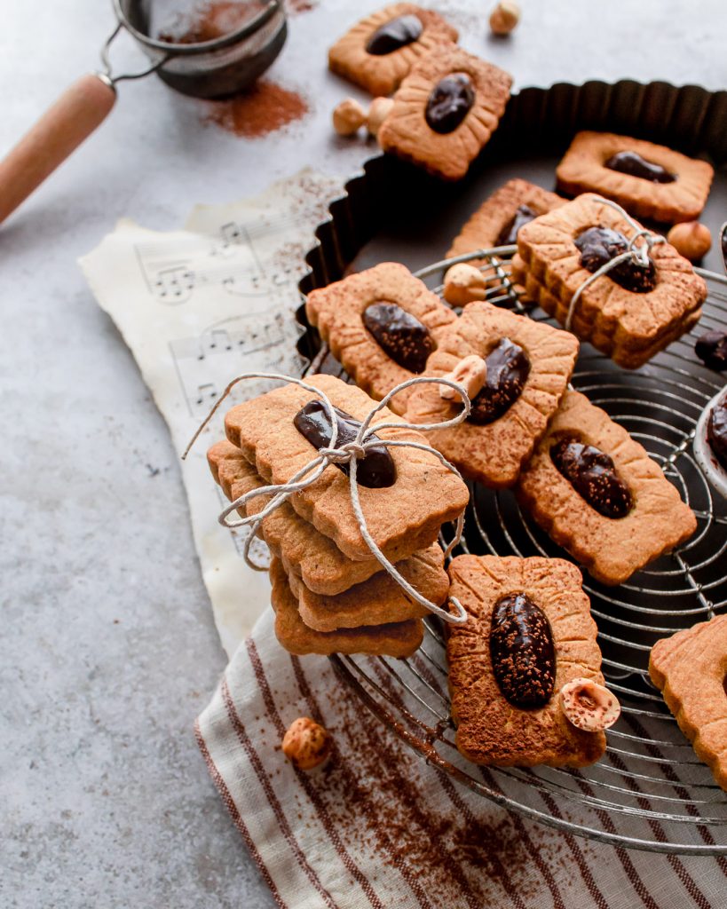 An arrangement of cookies on a round wire rack filled with chocolate. 